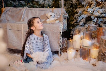 Beautiful smiling little girl playing near the christmas tree. Room decorated for New Year. Holiday atmosphere.の写真素材