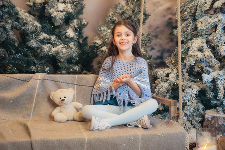 Beautiful smiling little girl playing near the christmas tree. Room decorated for New Yearの写真素材