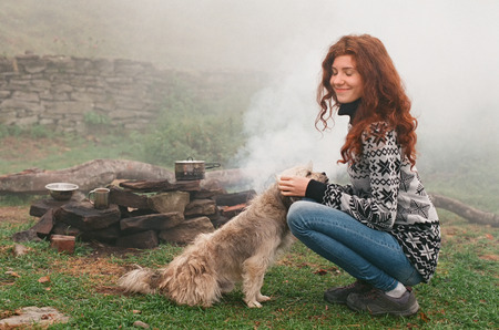 Happy woman playing with homeless dog in mountain camp. Friendship of people and animals. Scanned film with grainの写真素材