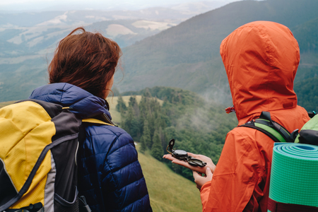 Two friends looking on compass and searching road while hiking in mountainsの写真素材