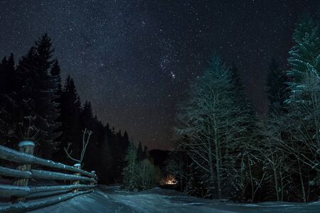Milky Way and full sky with stars over the mountain forest. Low light scene of winter landscape at night with fire on backgroundの写真素材