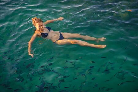 Happy woman swimming near coral reef with many fishes and clear blue water in Thailand on the Phangan island . Healthy lifestyle and vacation in tropical countiesの写真素材
