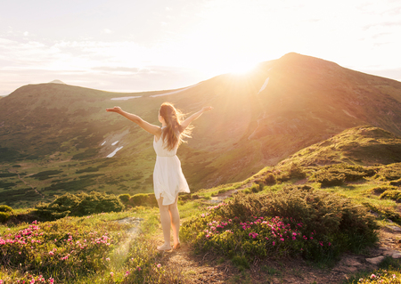 Happy woman enjoying the nature in the mountains and looking on sky with raised hands. Freedom conceptの写真素材