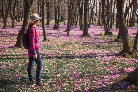 Happy woman enjoying the nature in the spring forest and feeling free among meadow of beautiful crocus flowers. Freedom and wanderlust travel conceptの写真素材