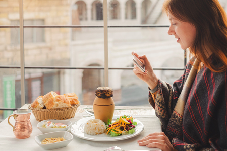 Young woman take photo on mobile phone of traditional  turkish food from pottery kebabの写真素材