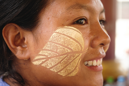Mandalay, Myanmar - May 17, 2016: Portrait happy burmese woman with traditional thanaka makeup in leaf shapeのeditorial素材
