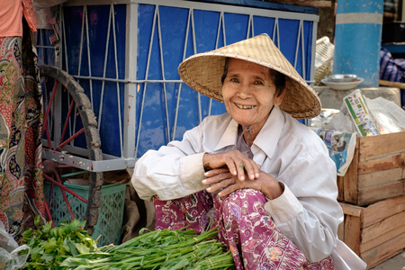 Mandalay, Myanmar - May 17, 2016: Portrait of old positive burmese woman with traditional hat on the Mandalay marketのeditorial素材