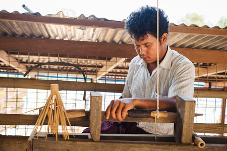 Kalaw, Myanmar - May 22, 2016: Burmese family have local business for traditional umbrella production from bamboo wood and handmade paper. Local man making in home workshop.のeditorial素材