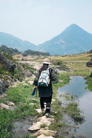 Sapa, Vietnam - April 14, 2016: Black Hmong minority woman in traditional clothes on rice terraces landscape in Sa Pa. Rural vietnamese paddy fieldsのeditorial素材