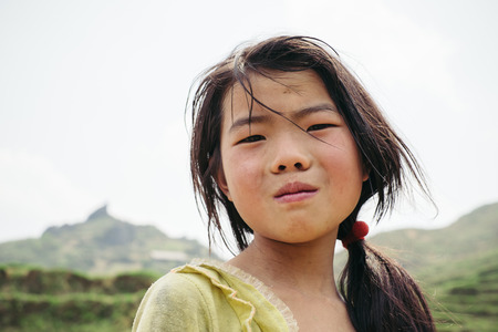 Sapa, Vietnam - April 14, 2016: Little asian girl from hmong tribe walking on mountain paddy field.のeditorial素材