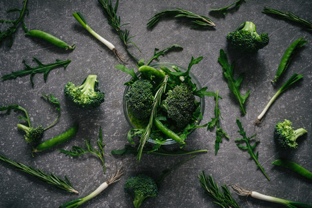 Top view of fresh variety greenery and vegetables on dark rustic table backgroundの写真素材