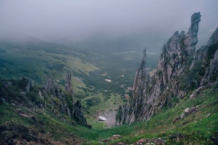 Dark mountain landscape with big mysterious rocks covered by fogの写真素材