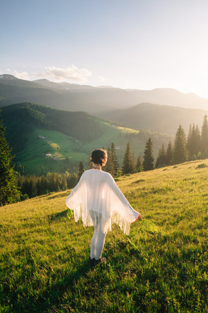 Woman feel freedom and enjoying the nature in the mountains green fern leaves in hands on sunsetの写真素材