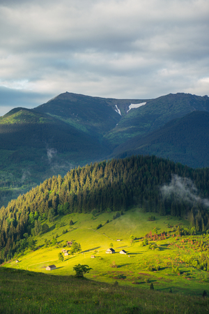 Mountain rural landscape with sun light on the green hills at sunrise.の写真素材