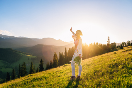 Woman feel freedom and enjoying the nature in the mountains green fern leaves in hands on sunsetの写真素材