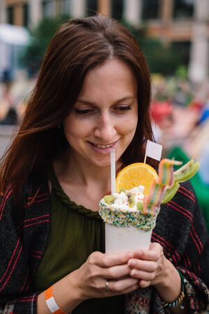 Woman drinking tasty milkshake dessert with fruits and creamの写真素材