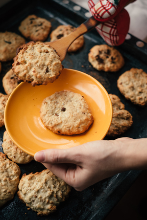 Woman takes tasty homemade cookies from the oven. Close-up sweet desert on dark panの写真素材