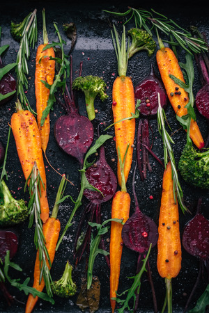 Top view of fresh vegetables, spices and herbs for roasting on rustic dark background, top viewの写真素材