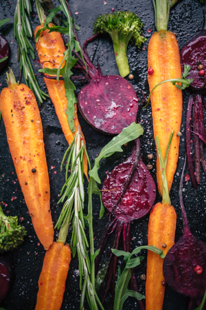 Top view of fresh vegetables, spices and herbs for roasting on rustic dark background, top viewの写真素材