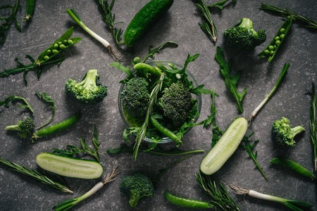 Top view of fresh variety greenery and vegetables on dark rustic table backgroundの写真素材