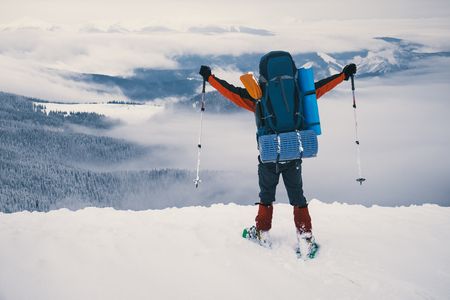 Tourist enjoying beautiful landscape and feel freedom in winter mountain at sunset. Winter sport activity. View from the back sideの写真素材