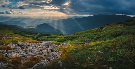 Dark mountain landscape with dramatic sky before the storm and sunbeam at sunsetの写真素材