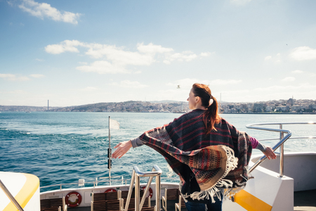 Happy female traveler on a ferry enjoying panorama view of Istanbul on a sunny dayの写真素材