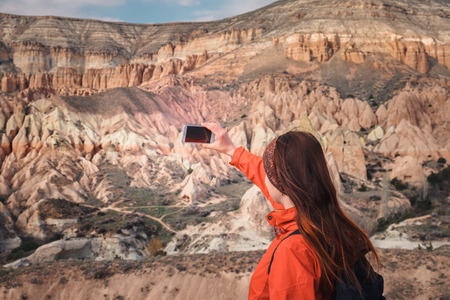 Female tourist taking picture on mobile in the rose valley in Cappadociaの写真素材