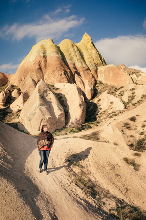 Tourist walking down the rock formations in the valley on a sunny day in Turkeyの写真素材