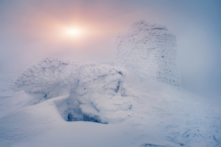 Beautiful winter landscape with snowy hills and abandoned observatory in the Carpathian mountains with walls covered by frost and ice in winterの写真素材