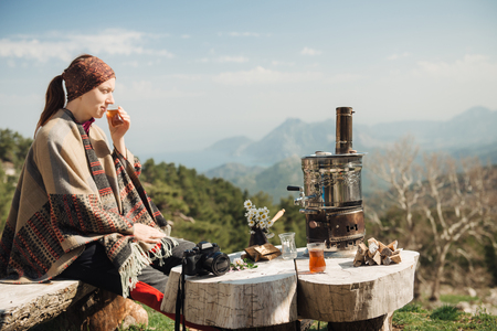 Young traveler having a Turkish tea at the wooden table high in the mountains.の写真素材