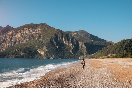 Tourist taking a walk on the lonely pebble beach along the sea shore on the background of Tahtaliの写真素材