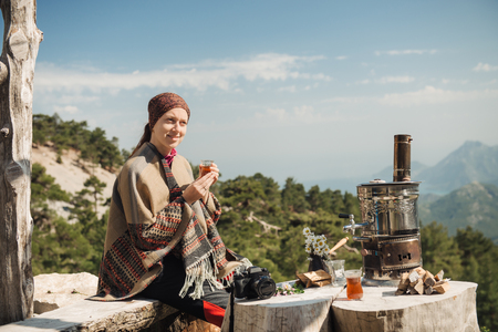 Young traveler having a Turkish tea at the wooden table high in the mountains.の写真素材