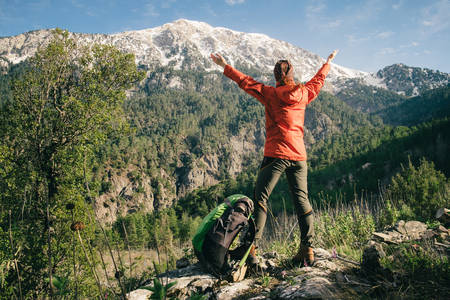Backpacker with her hands raised standing next to her backpack celebrating view of Tahtali on a sunny dayの写真素材