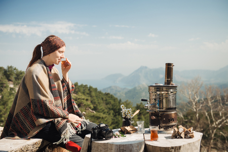 Young traveler having a Turkish tea at the wooden table high in the mountains.の写真素材