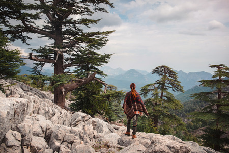 Single evergreen trees covering mountain sides of Tahtali and a young traveler (shot from back) taking a moment to witness beauty aroundの写真素材