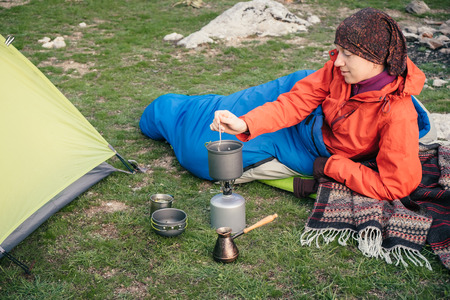 Tourist in a sleeping bag preparing food on the gas burner in the mountains in Turkeyの写真素材