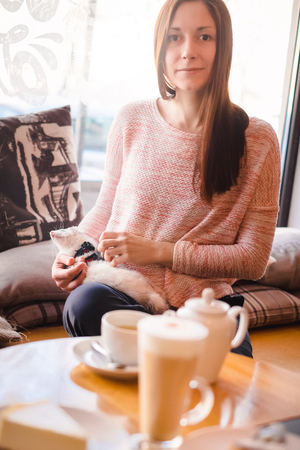 Beautiful girl with long brown hair having a good time with her favorite pet ferret at a cafe window sill. Woman and a pet concept.の写真素材