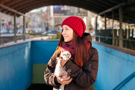 Young woman with her domestic pet ferret getting some fresh air on a sunny cold day in the city.Woman and a pet concept.の写真素材