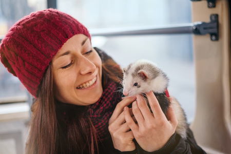 Sensual young woman with long hair hugging her pet ferret on a tram.Woman and a pet concept.の写真素材