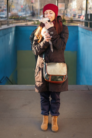 Young woman holding her pet ferret on the background of underpass on a sunny day. Woman and a pet concept.の写真素材
