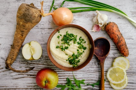 Parsnip soup with parsley and vegetables on wooden table, Top viewの写真素材