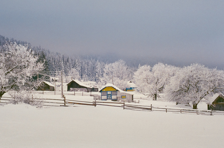 Panorama of an ordinary village life in snowy winter in Carpathians. Shot on film camera with noise and grainの写真素材