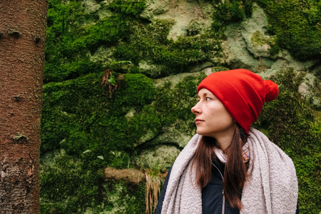 Portrait of young caucasian hiker posing in Carpathian forest on a green moss background looking at tree trunk, in Fall.の写真素材
