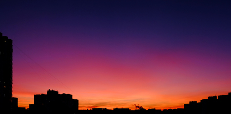 Unbelievable sunset like in a fairytale with saturated purple, pink, blue, and orange colors in the sky in the evening industrial city.の写真素材