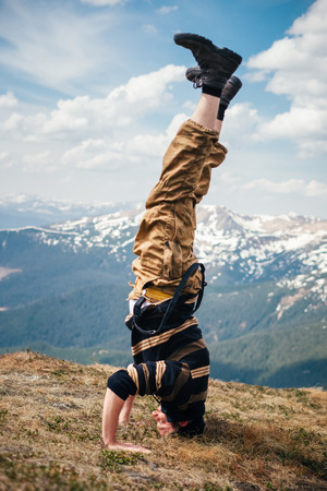 Male hiker practicing yoga headstand outdoors on a Carpathian mountains background on a Spring day. Concept of tourism. の写真素材