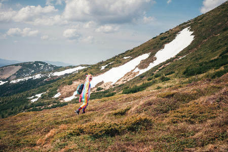 Funny backpacker in a unicorn costume hiking in the mountains. Travel and freedom conceptの写真素材