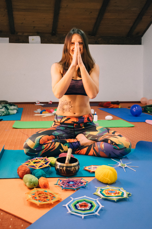 Happy smiling caucasian yoga instructor with henna tattoo on her side practicing on a mat in an empty class before knitting mandalas.の写真素材