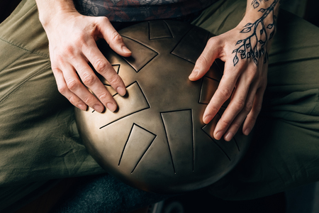 Closeup of a caucasian man playing tank drum with his hands covered with henna tattoo.の写真素材