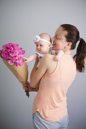 Dad presented a ping flowers bouquet for a mother with a newborn baby. Happy young familyの写真素材